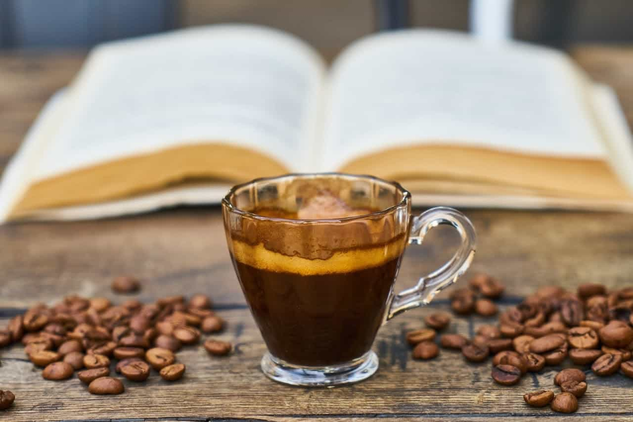 Xícara de café em cima de uma mesa com grãos de café em volta